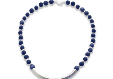 A necklace with dark blue round beads and a curved silver centerpiece.