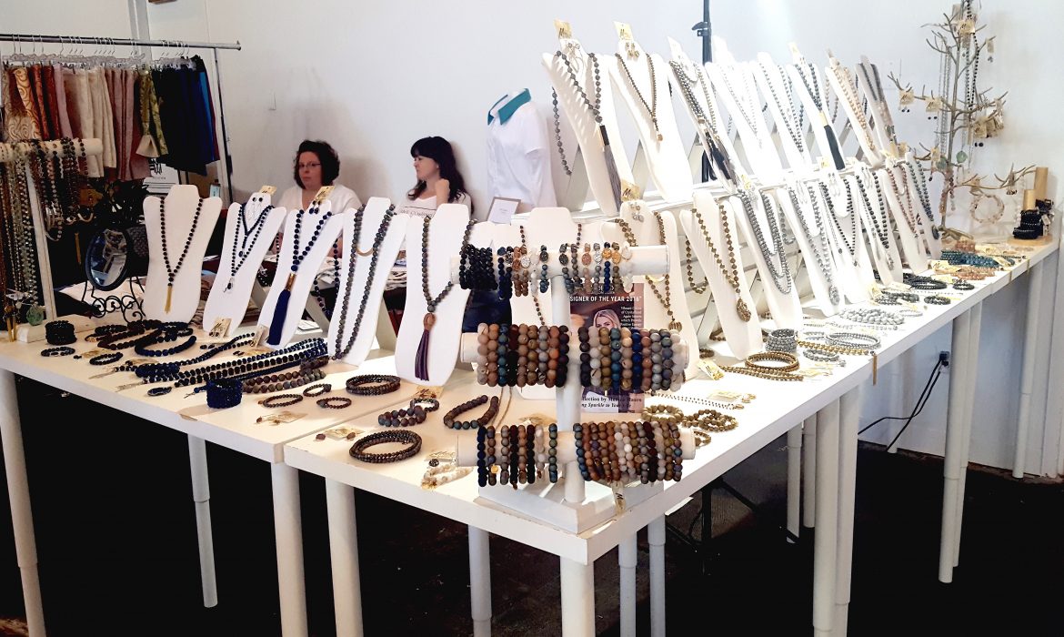 A display of jewelry including necklaces, bracelets, and rings on white tables.